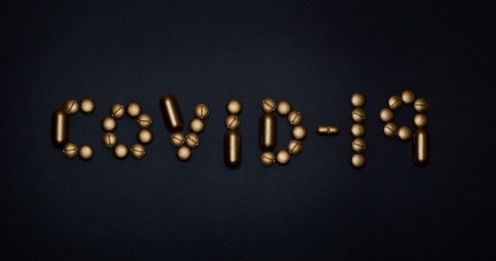 Artistic representation of COVID-19 using golden pills on a black background, symbolizing healthcare and treatments.